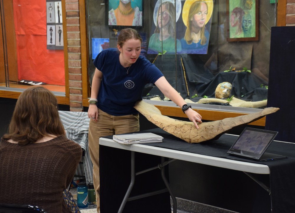 Locust Valley High School senior Clare Simon talks to fellow students about her IB Art works, including a wood carving project.