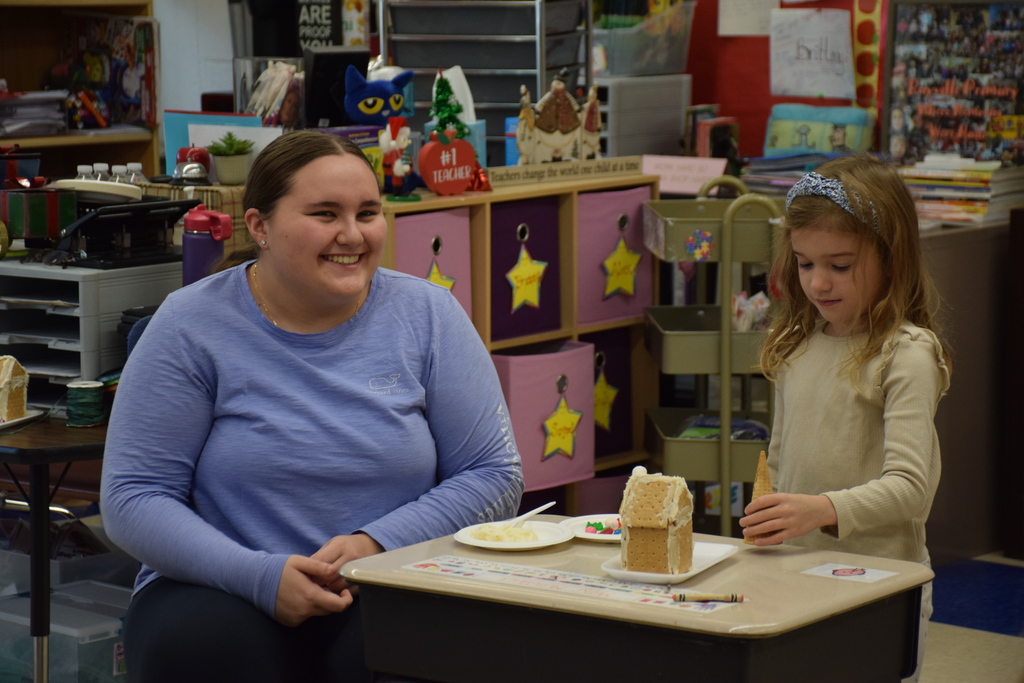 A member of the LVHS Interact Club helps a Bayville Primary student decorate her gingerbread house.