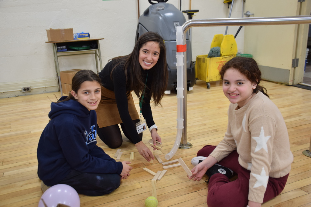 Melanie Smith, Mrs. Jennifer Pagan and Elisa Valle work on a project where a toy car would push a pin into a balloon.