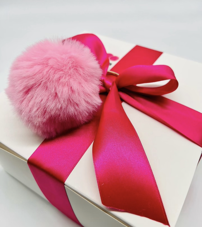 One of Palleschi’s Pink Pom Pom boxes, filled with candles, socks, notepads, pens, bath salts, shower salts, hand lotions, tumblers and inspirational note cards along with a signature pink pom pom keychain for breast cancer patients.